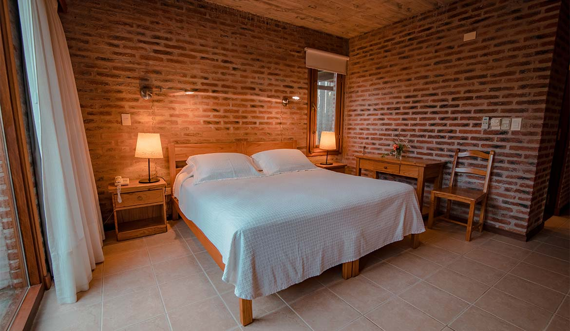 Habitación con cama matrimonial y paredes de ladrillo